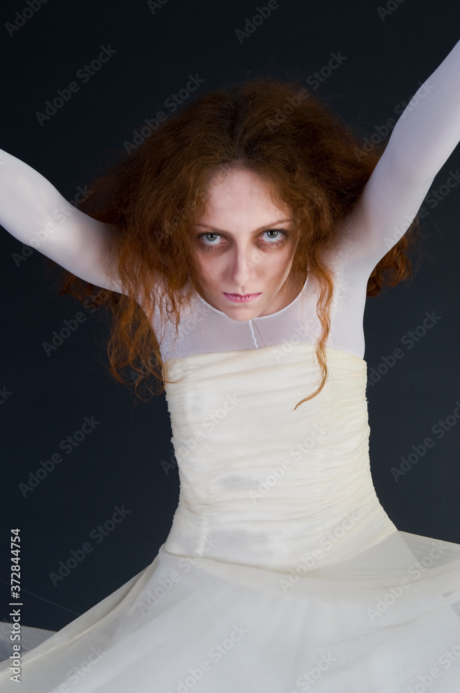 Fototapeta premium An image for halloween, a red-haired woman in the image of a witch in a white outfit with a pale deathly face