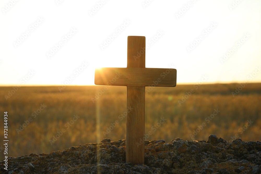 Wooden Christian cross outdoors at sunrise. Religion concept