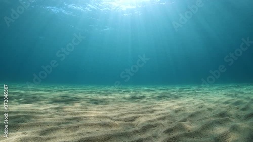 Underwater seascape, sandy seafloor and rays of sunlight below water surface in the Mediterranean sea, natural scene, France photo
