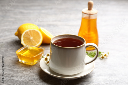 Tea with honey and lemon on grey table