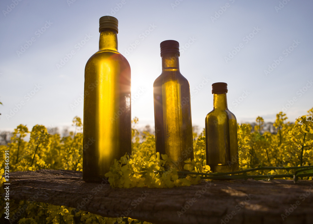 Rapeseed flowers and rapeseed oil in a set bottle on the table. Rapeseed flowers and rapeseed oil in a set bottle on the table.