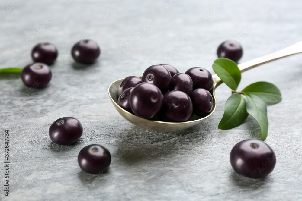 Fresh acai berries and spoon on light grey table, closeup Fresh acai berries and spoon on light grey table, closeup