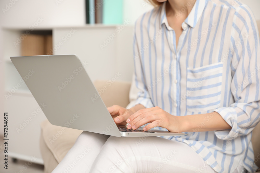 Young woman with laptop sitting indoors, closeup