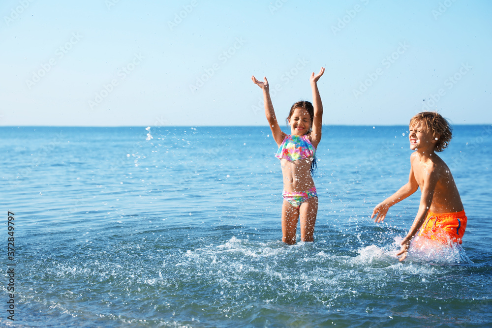 Cute little children having fun in sea on sunny day. Beach holiday Cute little children having fun in sea on sunny day. Beach holiday