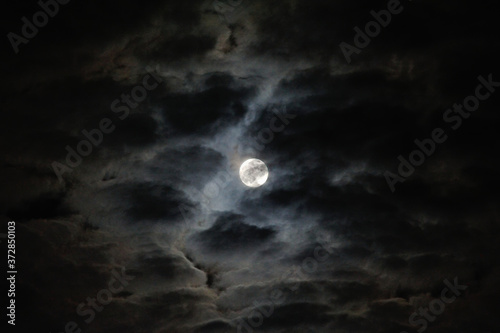 the full moon shining through clouds