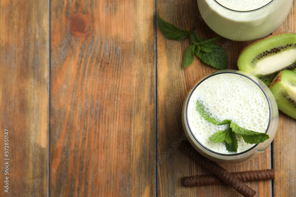 Tasty milk shake with kiwi on wooden table, flat lay. Space for text Tasty milk shake with kiwi on wooden table, flat lay. Space for text