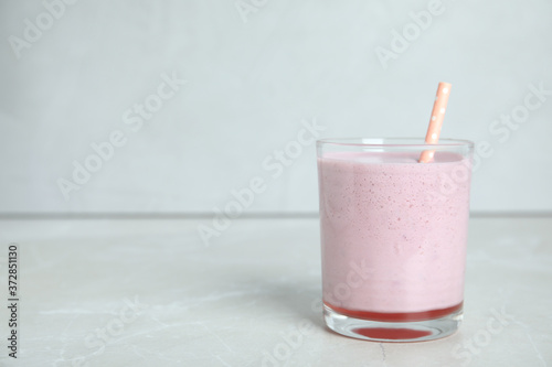 Tasty milk shake with straw on light grey table. Space for text