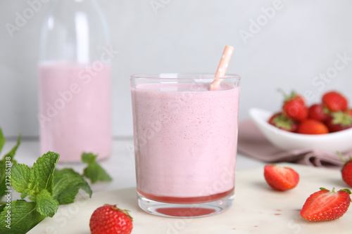 Tasty milk shake with strawberries and mint on table