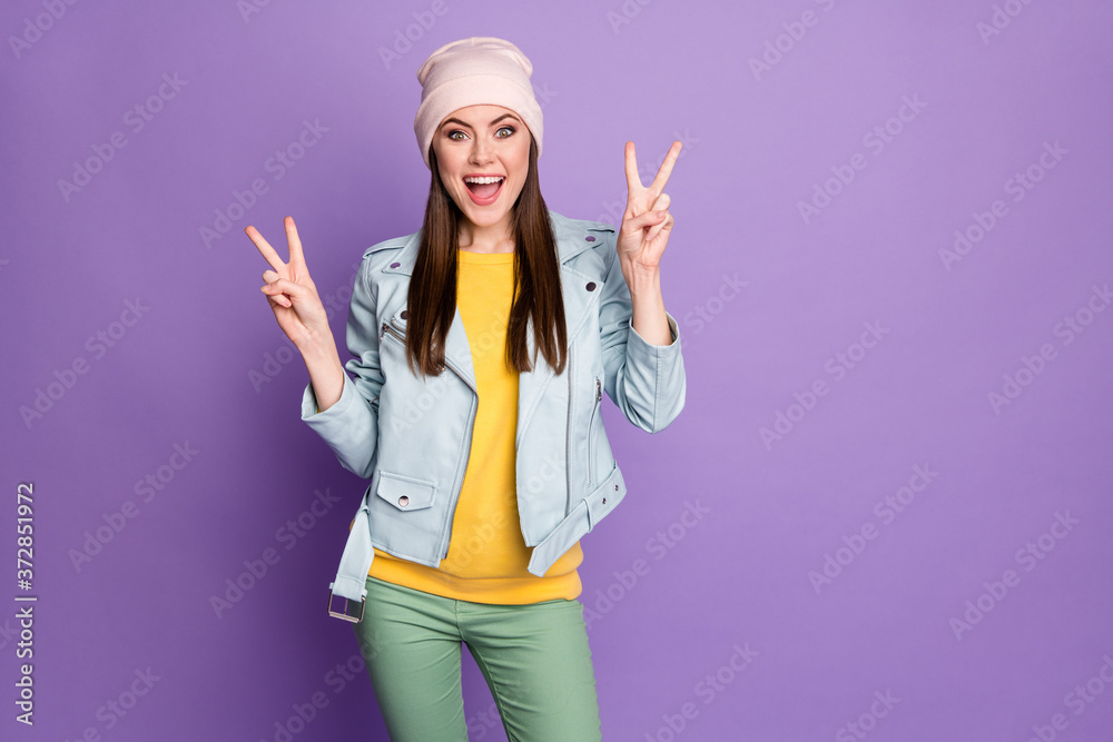 Photo of crazy funky attractive lady good mood showing v-sign symbols hands cheerful person teenager wear casual hat blue modern jacket pants isolated purple color background Photo of crazy funky attractive lady good mood showing v-sign symbols hands cheerful person teenager wear casual hat blue modern jacket pants isolated purple color background