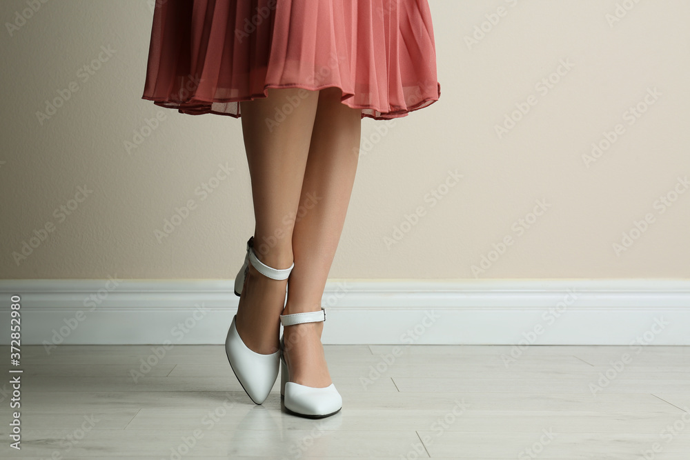 Woman wearing stylish shoes near beige wall indoors, closeup Woman wearing stylish shoes near beige wall indoors, closeup