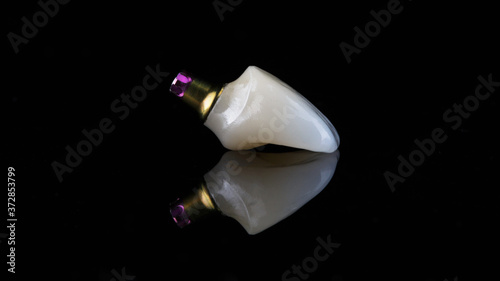 very beautiful dental crown made of anterior incisor ceramic, on black glass with creative reflection