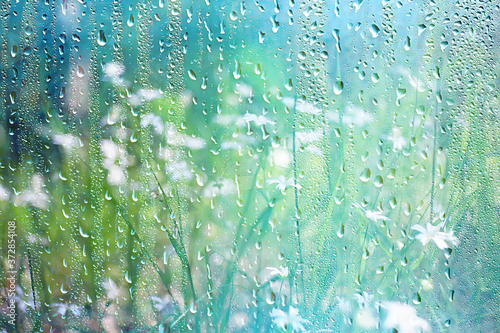 summer rain wet glass / abstract background landscape on a rainy day outside the window blurred background
