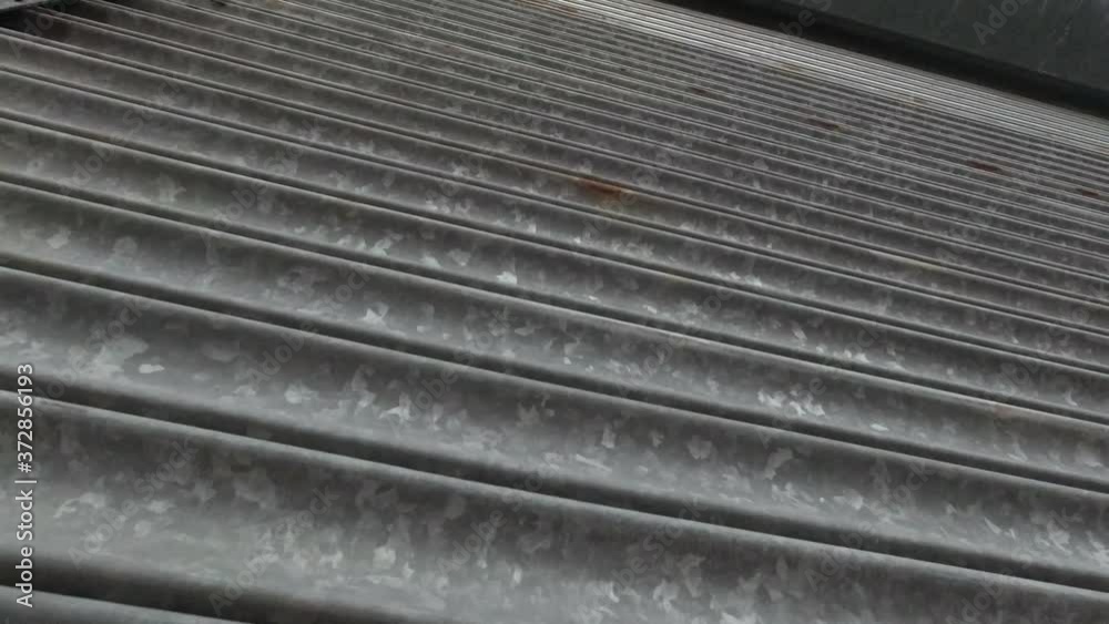 Corrugated metal store roller shutters opening low angle closeup