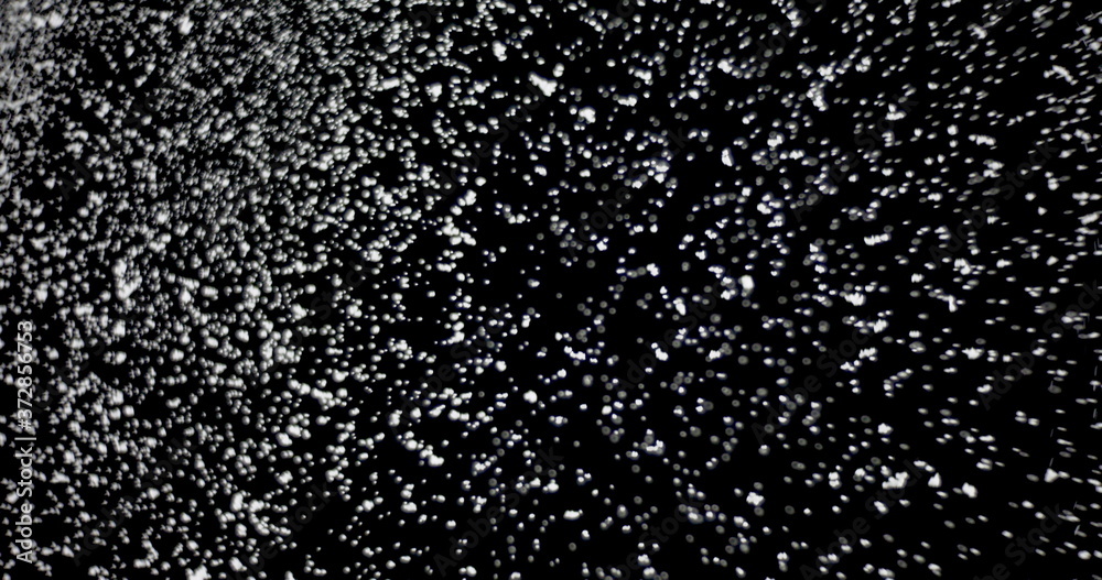 Cloud of shiny snowflakes floating in the air. The shot was taken while the snowflakes were on an isolated black background.