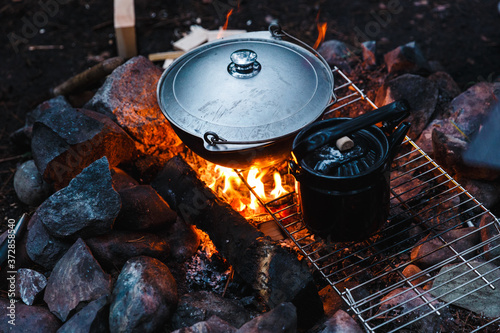 Summer outdoor rest. Camping in the forest in mountains. Cauldron and teapot on campfire. Cooking camp food