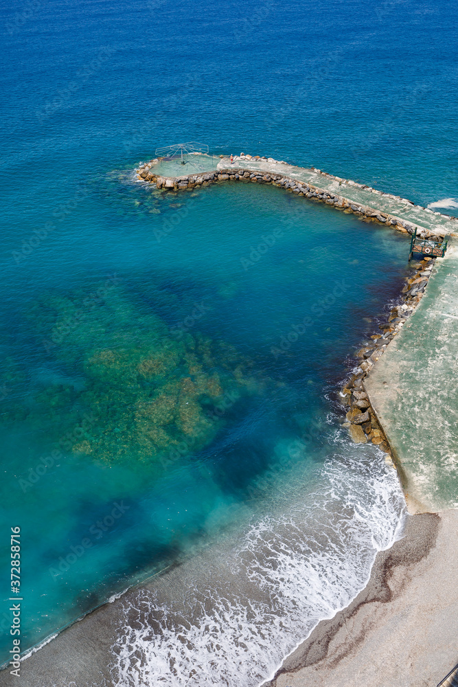 Top view of the sea shore with azure water and a sandy beach. Aerial view of the middle earth sea with coastline. Beautiful tropical sea in summer season, shot from drone