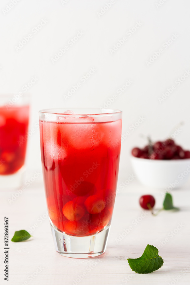 Summer delicious refreshing cherry compote with pulp and with ice in glasses on a white background Summer delicious refreshing cherry compote with pulp and with ice in glasses on a white background
