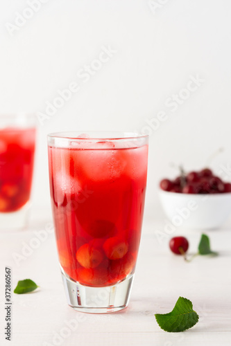 Summer delicious refreshing cherry compote with pulp and with ice in glasses on a white background
