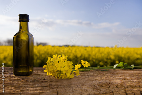 Dark bottle with oil on a background of rape flowers.