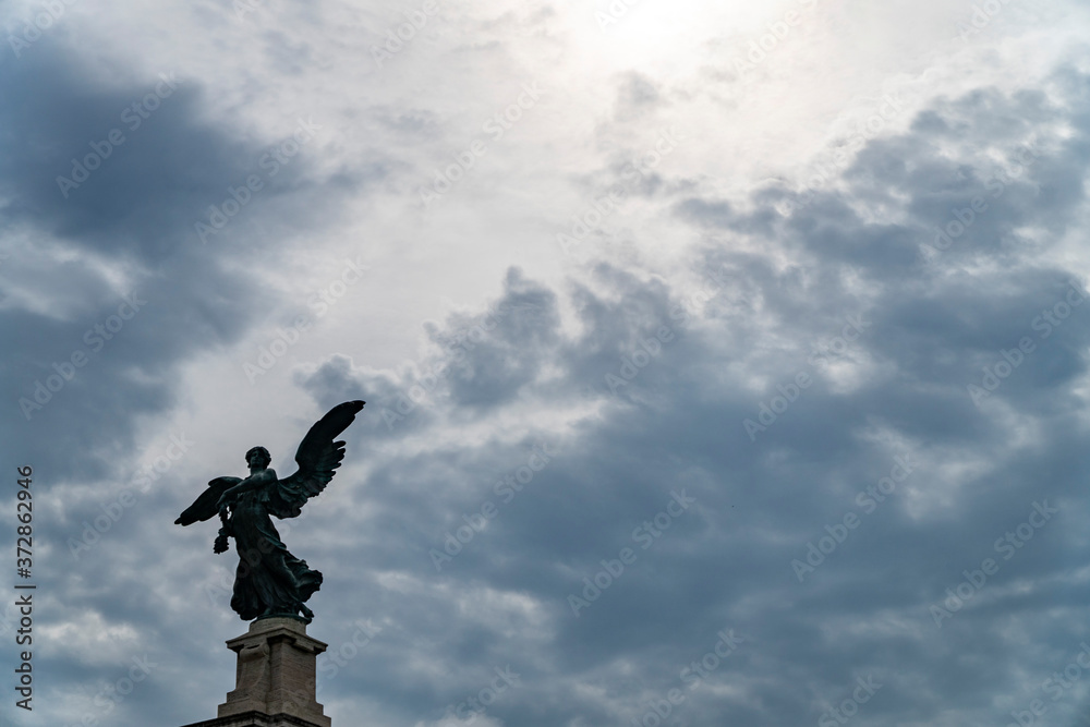 Statue of an angel in Rome and clouds background with sun rays as divine light Statue of an angel in Rome and clouds background with sun rays as divine light