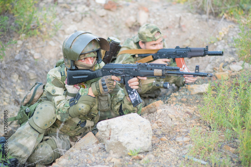 Two teammates of the airsoft player aim towards the enemy photo