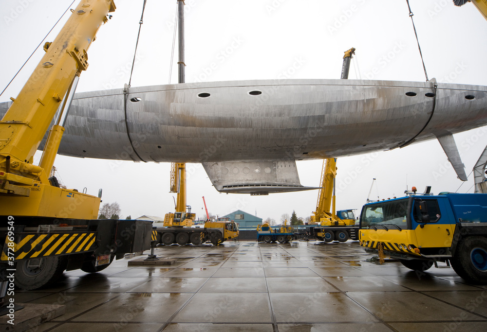 Turning of the hull with cranes. Aluminium hull of a super sailing yacht. Ship building industry. Turning of the hull with cranes. Aluminium hull of a super sailing yacht. Ship building industry.