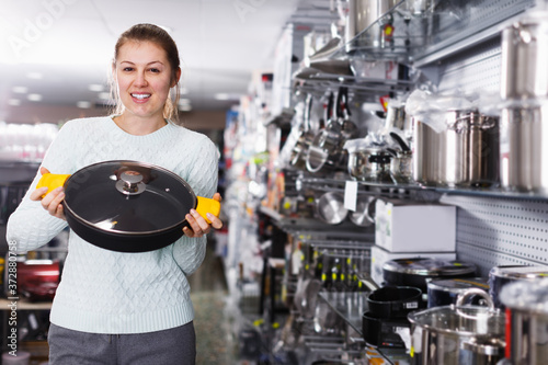 Young woman is choosing modern kitchen dripping pan for her home in the shop