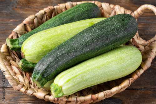 Raw zucchini. Zucchini in a basket on a brown wooden table