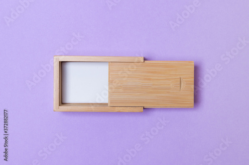 open wooden box with place for you logo on purple colored paper background. top view