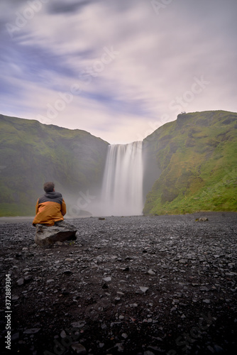 Man looking at the beautiful landscape of the skogafoss waterfall in iceland