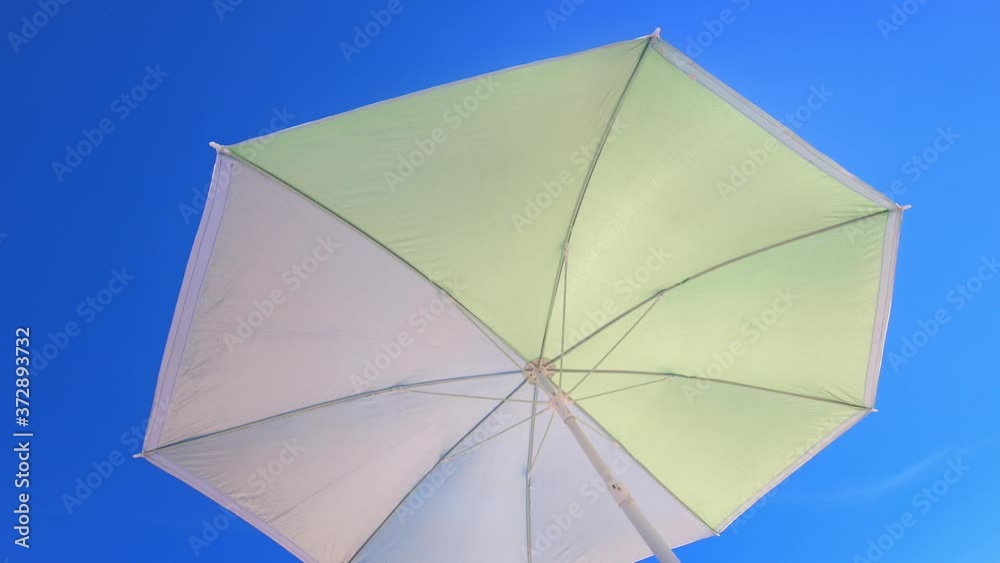Low angle view of a Sun umbrella sunshade in a beach with blue sky in background Low angle view of a Sun umbrella sunshade in a beach with blue sky in background