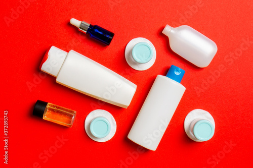 Set of travel size cosmetic bottles on colored background. Flat lay of cream jars. Top view of bodycare style concept
