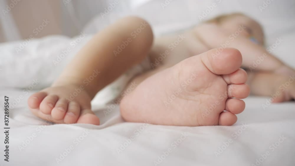 Little feet of a newborn baby. Baby sleeping sweetly in a comfortable bed. Little baby feet skin in close-up, selective soft focus. Little feet of a newborn baby. Baby sleeping sweetly in a comfortable bed. Little baby feet skin in close-up, selective soft focus.