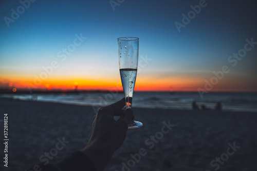 Glass with prosecco on the beach while sunset