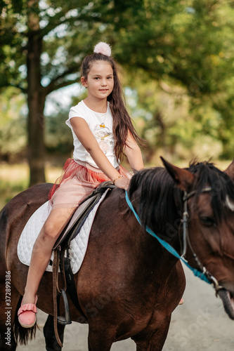 Emotional contact with the horse. Horse riding. The girl rides a horse in the summer. © sergo321