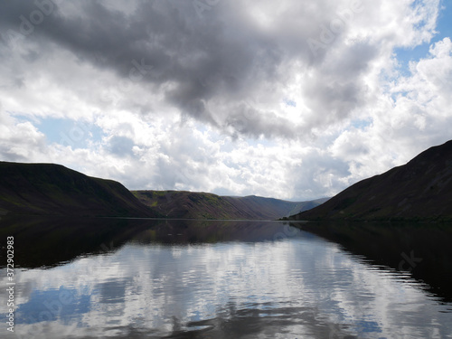 lake sorrounded by hills reflected in the water, grey clouds on the sky