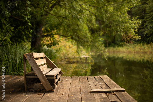 Wooden bench on the deck on the lake surrounded by greens photo