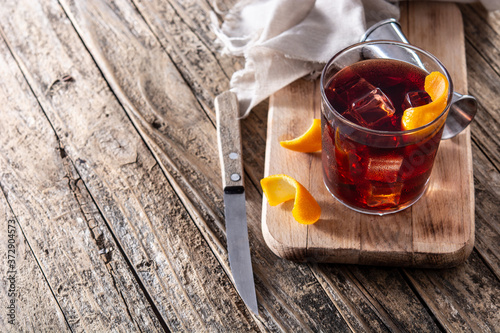 Boulevardier cocktail and orange zest on wooden table. Copy space	