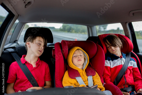 Fotografía Three children, boys, traveling in car in carseat sleeping tired after tiring da