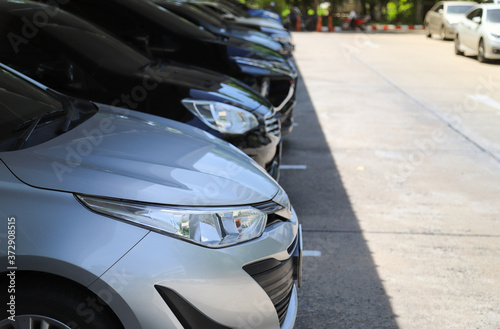 Closeup of front side of bronze city car with  other cars parking in indoor parking area in sunny day. 