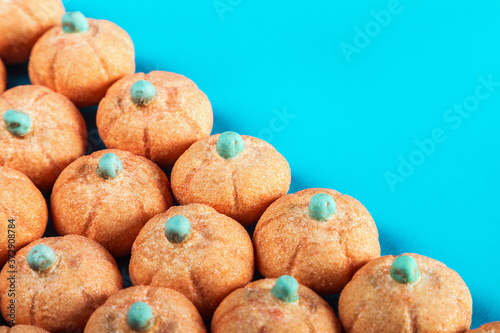 small marshmallow pumpkins with a sprinkle of sugar on a colored background. Decorations for the Halloween holiday