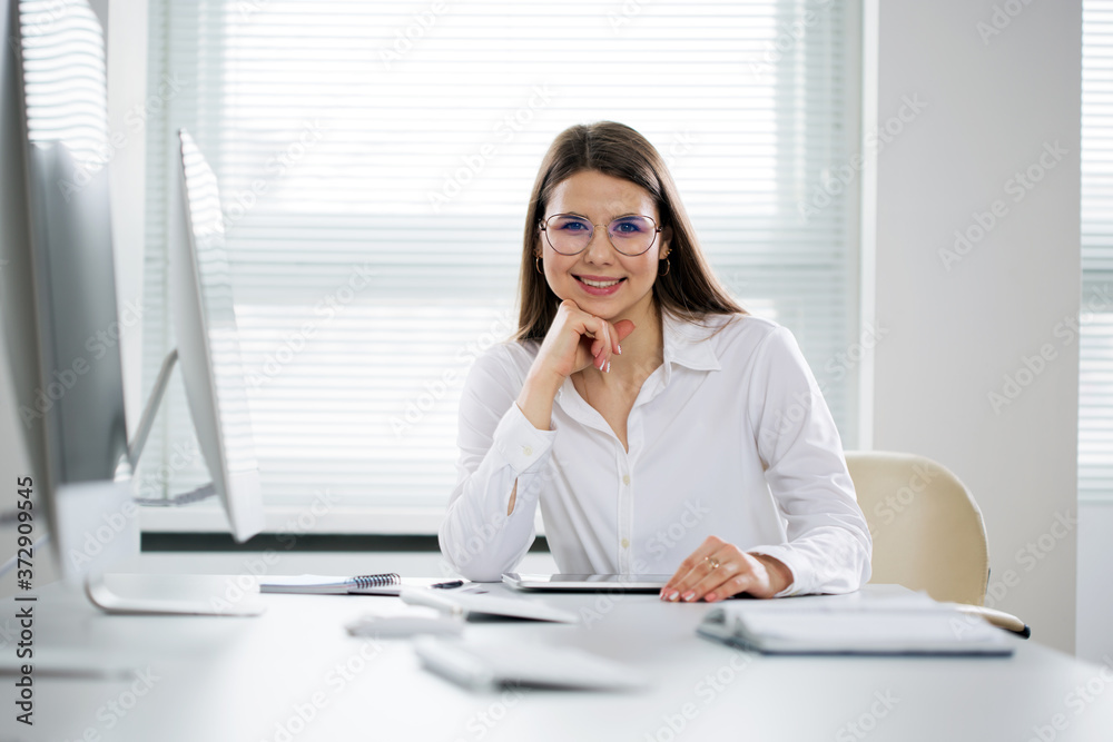 Portrait of business woman looking at camera at workplace in an office Portrait of business woman looking at camera at workplace in an office