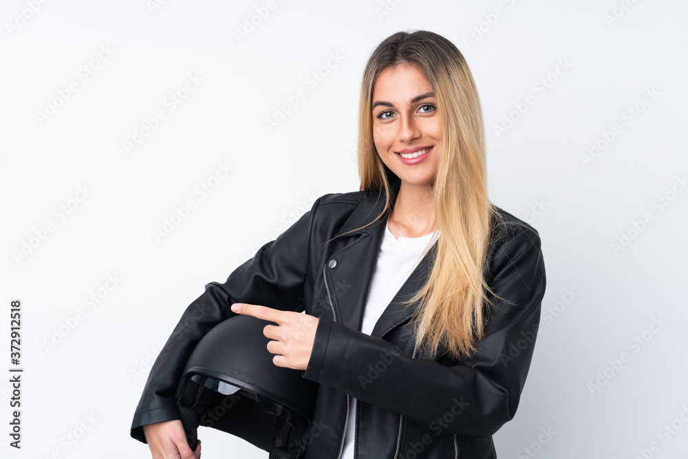 Young Uruguayan woman with a motorcycle helmet over isolated white background pointing finger to the side Young Uruguayan woman with a motorcycle helmet over isolated white background pointing finger to the side