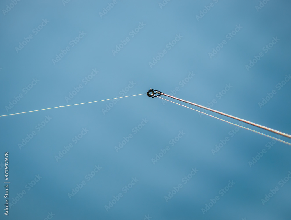 A monofilament fishing line on a fishing rod ring against blue water.