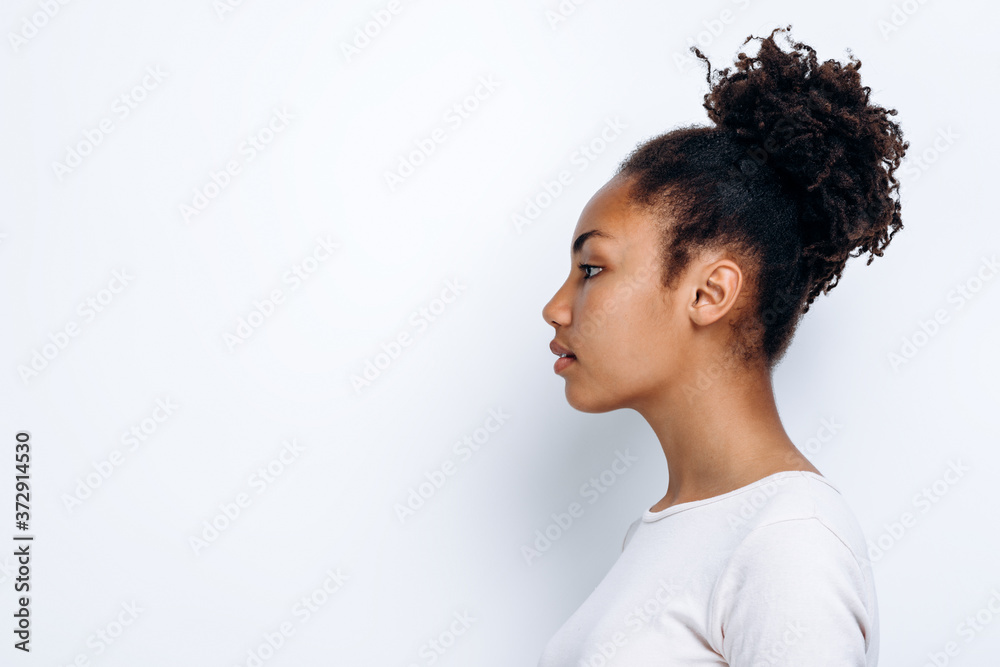 On a white background, an African-American girl stands in profile On a white background, an African-American girl stands in profile