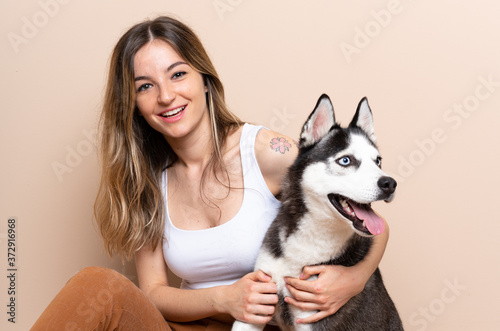 Young pretty woman with her husky dog sitting in the floor at indoors