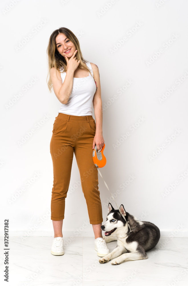 A full length young pretty woman with her dog smiling