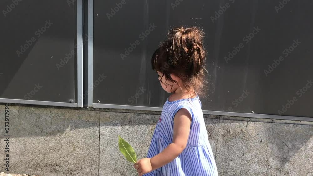 Niña paseando al lado de una pared