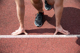 A starting position of a sprinter on a running track, close-up on hands and feet.