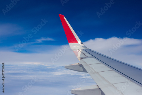 Wing airplane flying above on blue sky with clouds